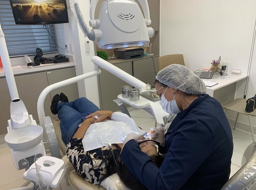 Profissional da Magnus Odontologia atendendo paciente em consultório equipado